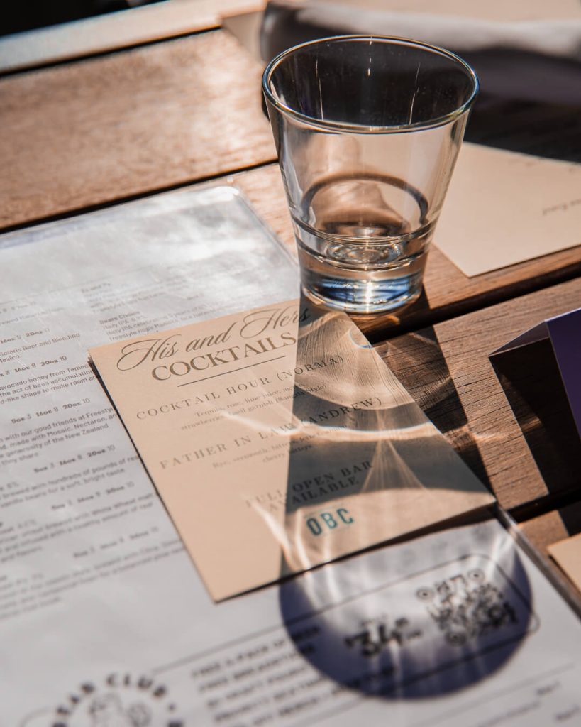 A cocktail menu and drinking glass arranged on a table in a stylish private event space.