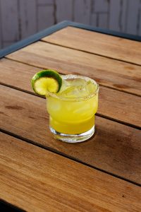 A handcrafted lime-garnished cocktail served on a wooden table.