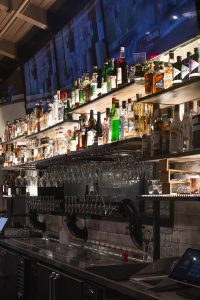 A fully stocked restaurant bar featuring shelves of spirits, glassware, and a polished countertop.