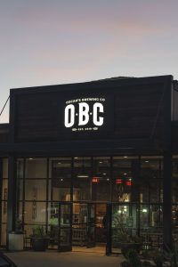 Exterior view of a modern restaurant with illuminated signage at dusk.